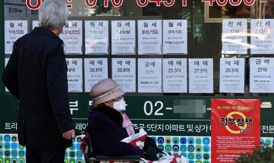 한 시민이 부동산 시세와 정부의 정책을 규탄하는 포스터가 걸린 부동산공인중개업소 매물정보 게시판을 살펴보고 있다. <연합뉴스>